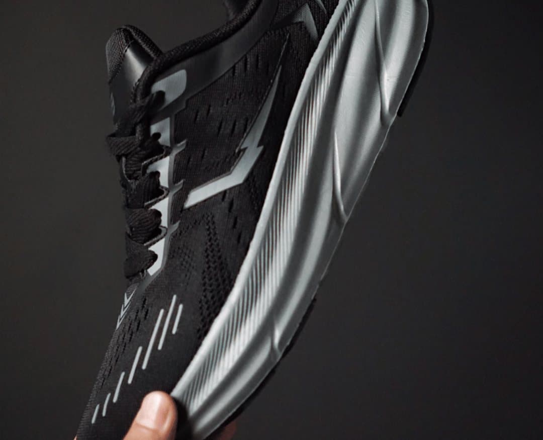 Hand holding a black Morph Lite runner showing its knit upper and grey midsole